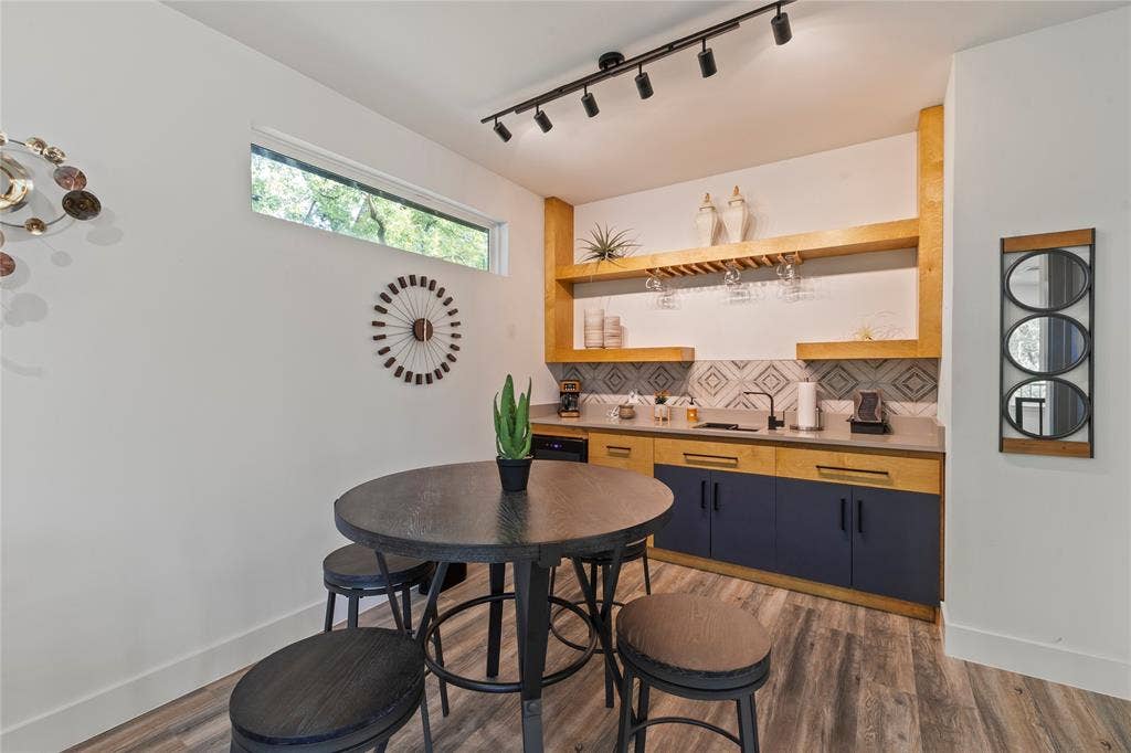 6113 Ottawa Trail, Mabank, TX 75156 Built-in bar featuring custom dual-tone cabinetry, natural wood floating shelving, stone-finish countertops, geometric tile backsplash, and overhead track lighting