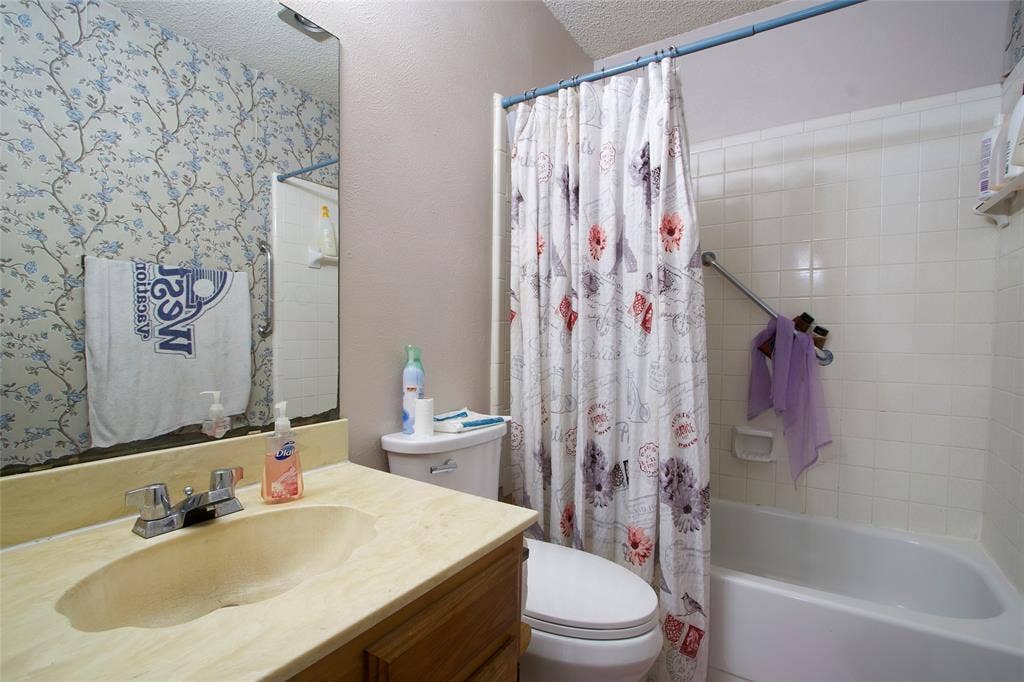 626 Thornwood Trail, Grand Prairie, TX 75052 Bathroom featuring a vanity with an integrated sink and countertop, a wall-mounted mirror, and a tub-shower combination with ceramic tile surround