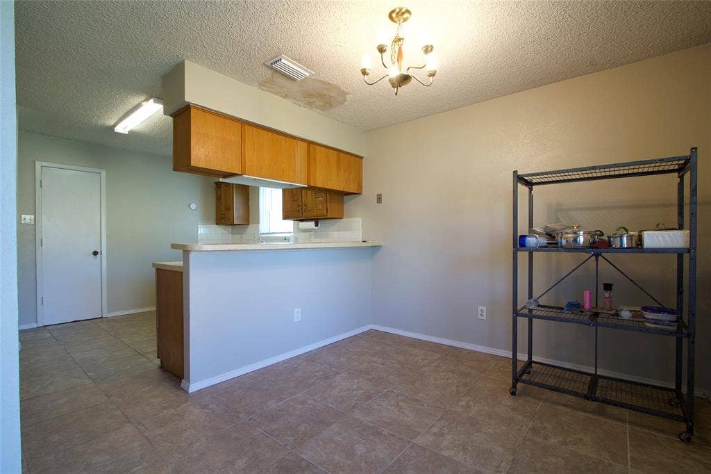 626 Thornwood Trail, Grand Prairie, TX 75052 Kitchen area featuring wood cabinetry, ceramic tile flooring, a peninsula counter, and a multi-arm chandelier