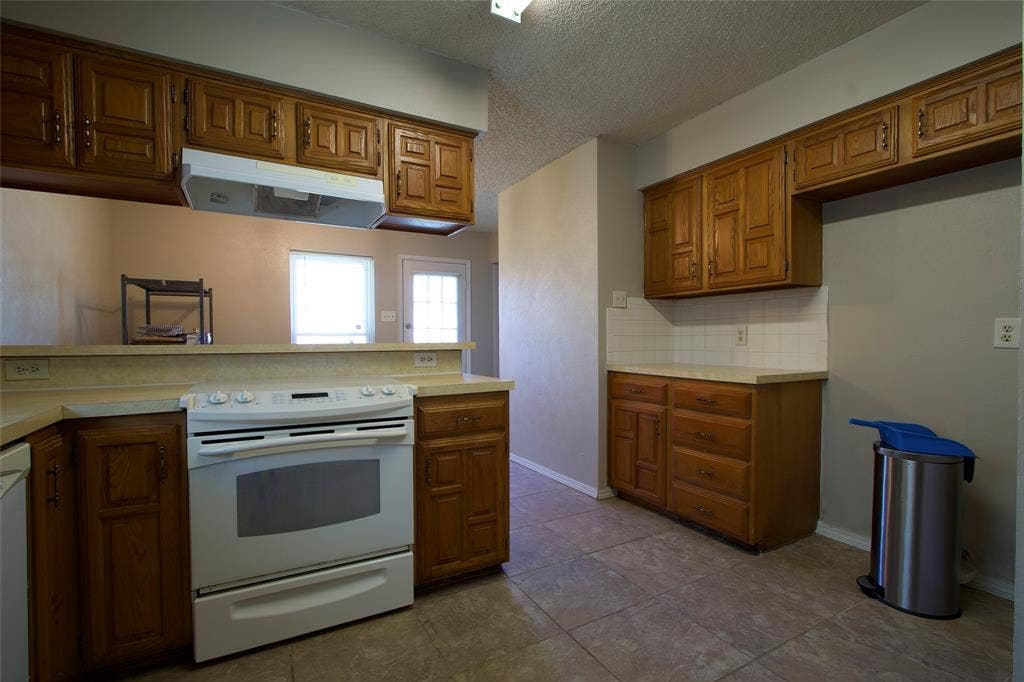 626 Thornwood Trail, Grand Prairie, TX 75052 Kitchen featuring wood cabinetry, tile flooring, stone-finish countertops, and a white range