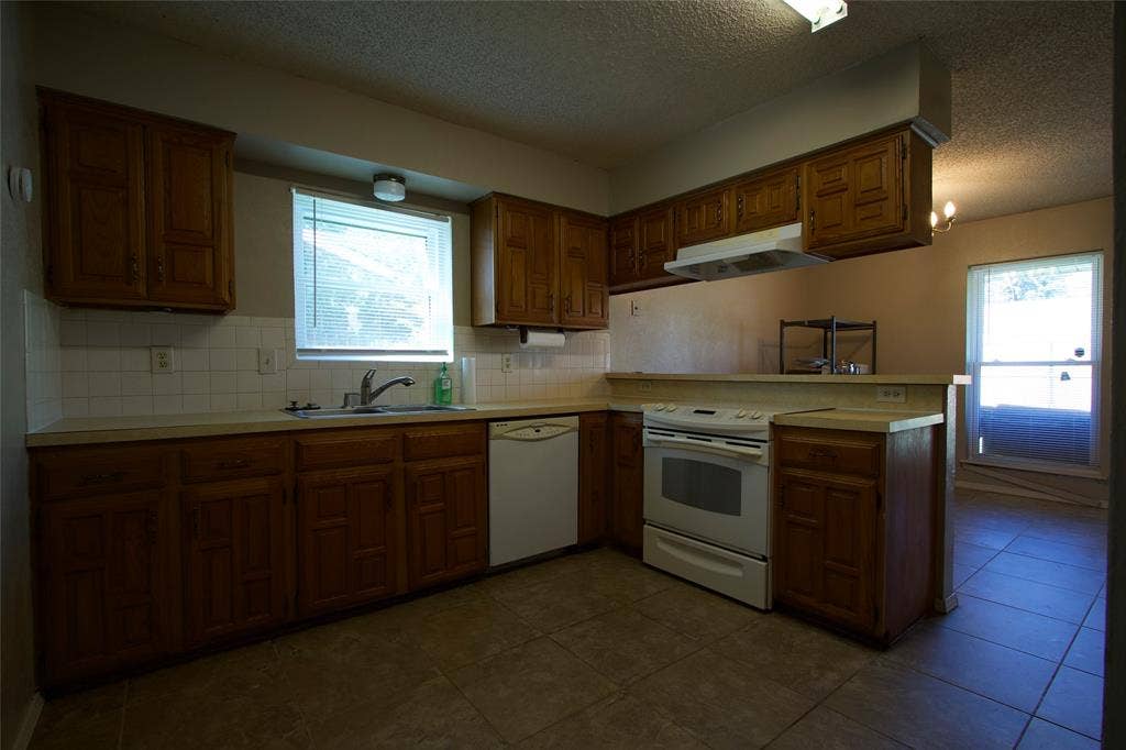 626 Thornwood Trail, Grand Prairie, TX 75052 Kitchen featuring wood cabinetry, tile flooring, white tile backsplash, integrated range hood, and double-basin sink