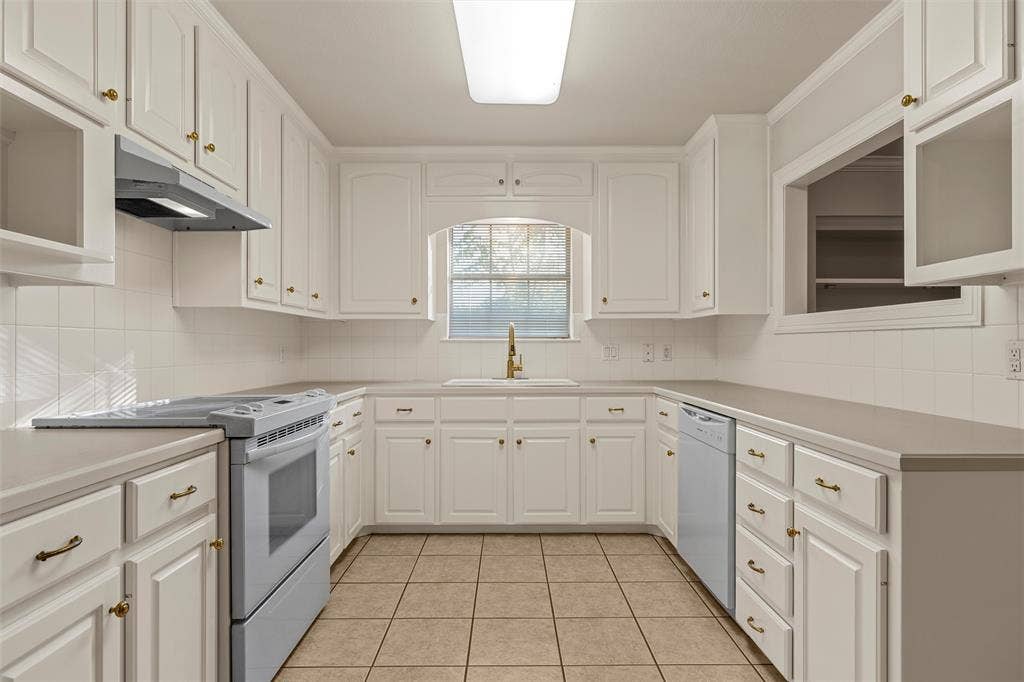 201 Pecan Village Circle, Waco, TX 76710 Kitchen featuring white cabinetry, solid-surface countertops, tile flooring, ceramic tile backsplash, and an arched window over the sink