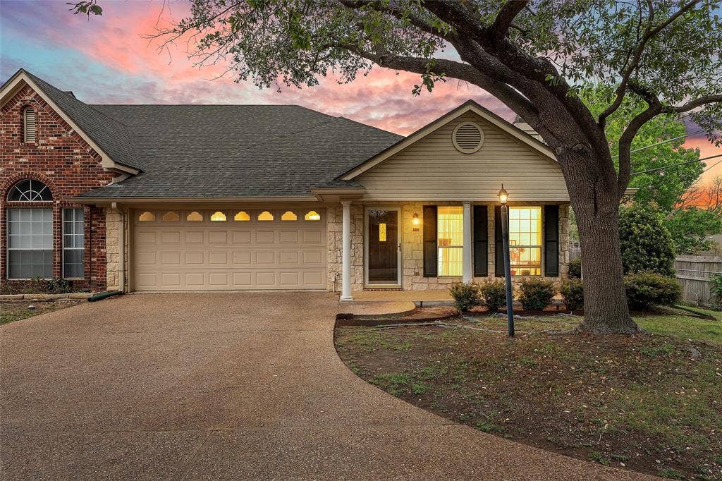 201 Pecan Village Circle, Waco, TX 76710 Multi-textured exterior facade featuring red brick, stone masonry, and horizontal siding, combined with a multi-gabled roofline, an arched window detail, and an aggregate concrete driveway