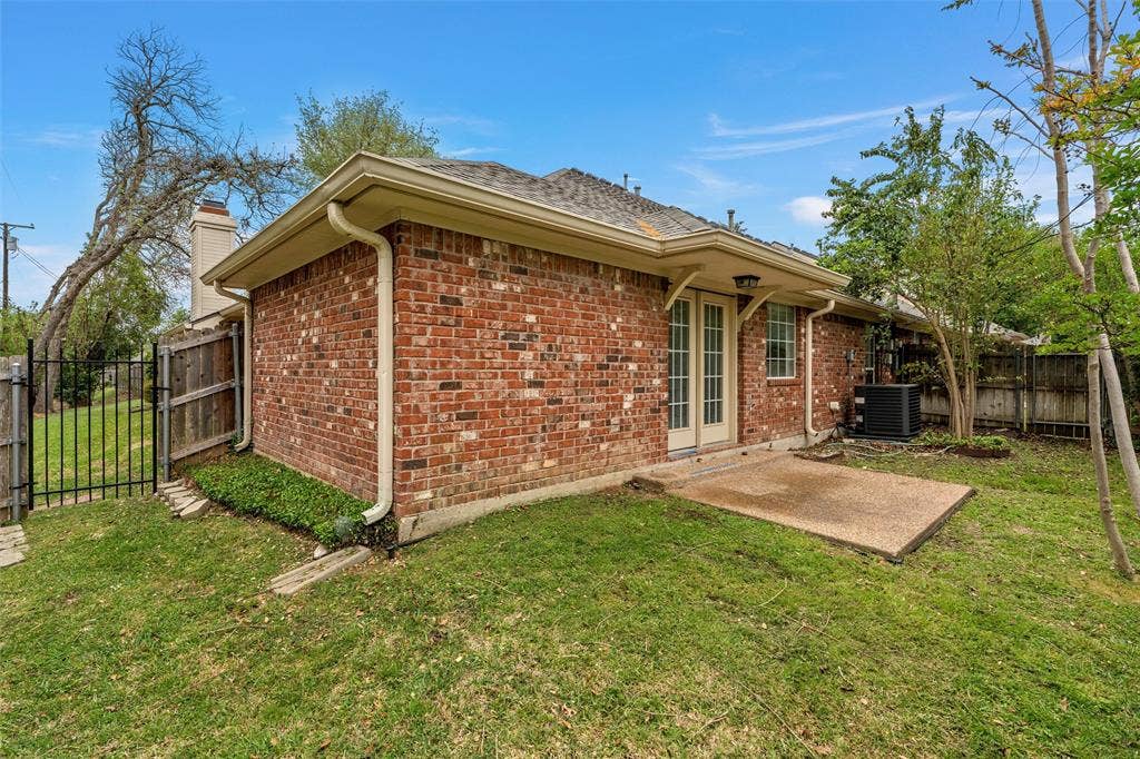 201 Pecan Village Circle, Waco, TX 76710 Rear exterior featuring red brick masonry, a concrete patio, French doors, and metal perimeter fencing