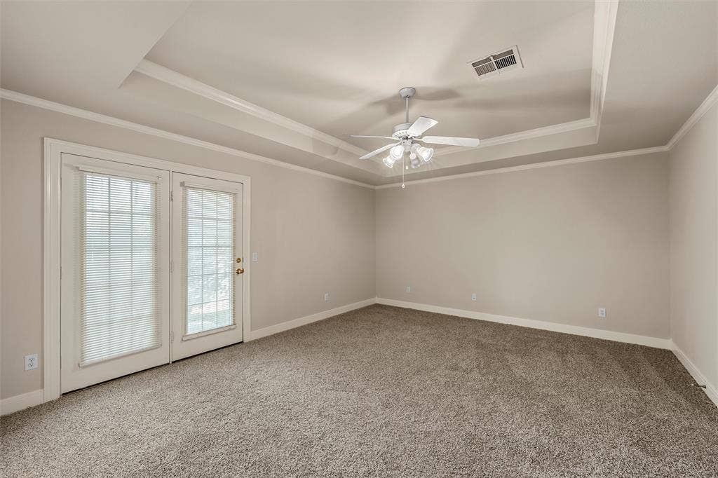 201 Pecan Village Circle, Waco, TX 76710 Tray ceiling with crown molding, neutral carpeting, and glass-paned double doors leading to the exterior
