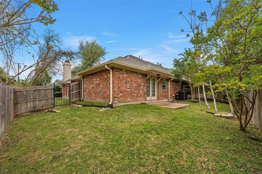 201 Pecan Village Circle, Waco, TX 76710 Brick exterior featuring a concrete patio, wood fencing, and mature landscaping