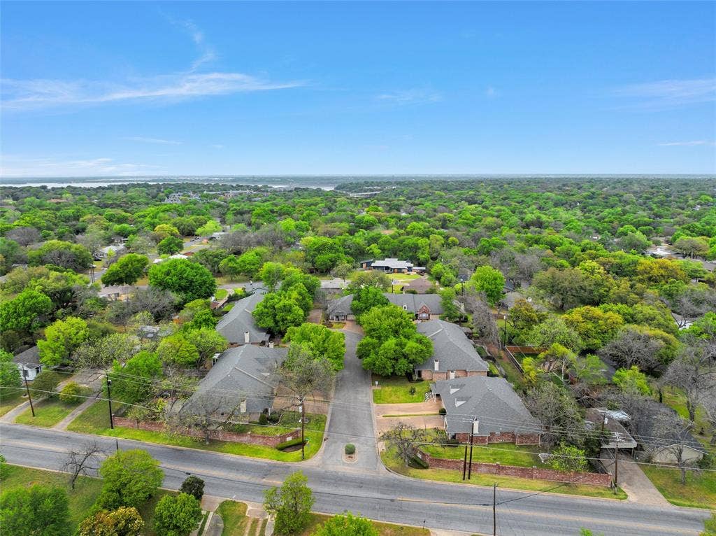 201 Pecan Village Circle, Waco, TX 76710 Aerial perspective featuring asphalt roadways, brick perimeter walls, mature trees, and shingled roof structures