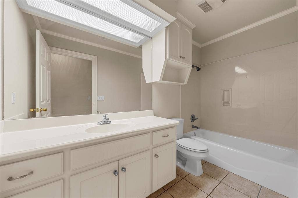 201 Pecan Village Circle, Waco, TX 76710 Bathroom featuring a white vanity with integrated basin, solid surface countertop, large wall-mounted mirror, overhead cabinetry, and a shower-tub combination with tile-surround