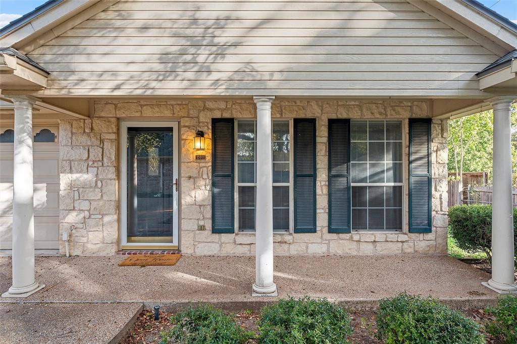 201 Pecan Village Circle, Waco, TX 76710 Covered front porch featuring a stone facade, decorative columns, exterior shutters, and horizontal siding