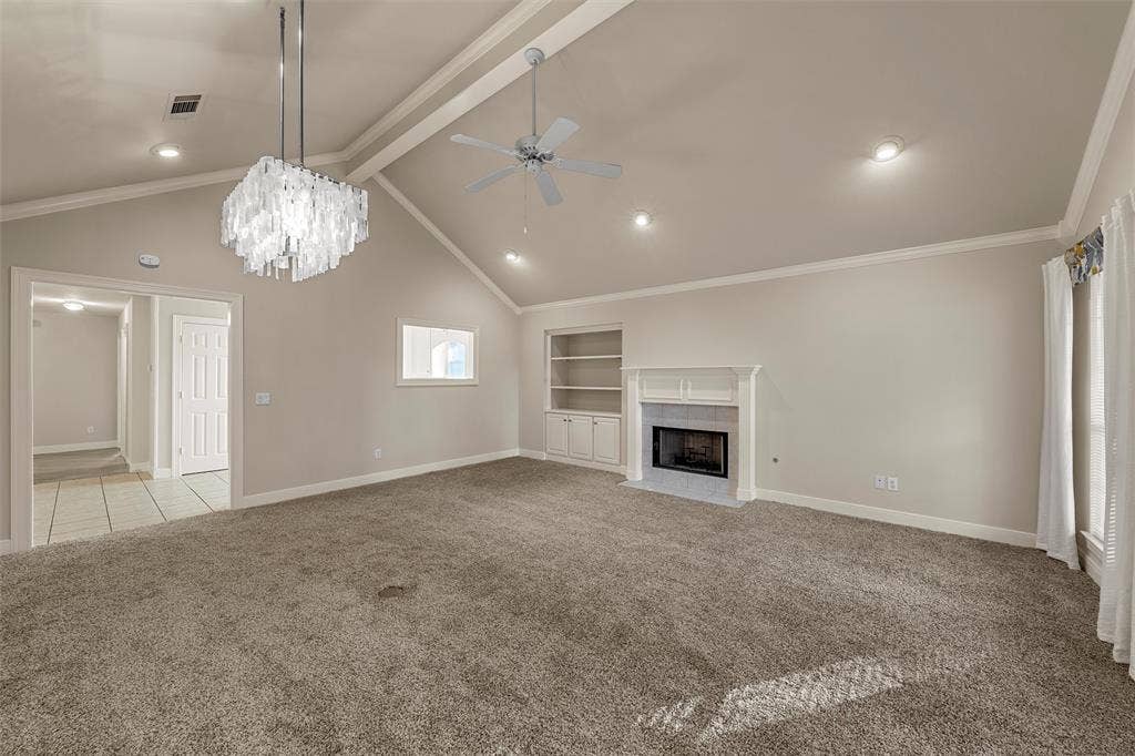 201 Pecan Village Circle, Waco, TX 76710 Vaulted ceiling featuring recessed lighting, a central crystal chandelier, and a ceiling fan, complemented by a stone-surround fireplace and custom built-in cabinetry