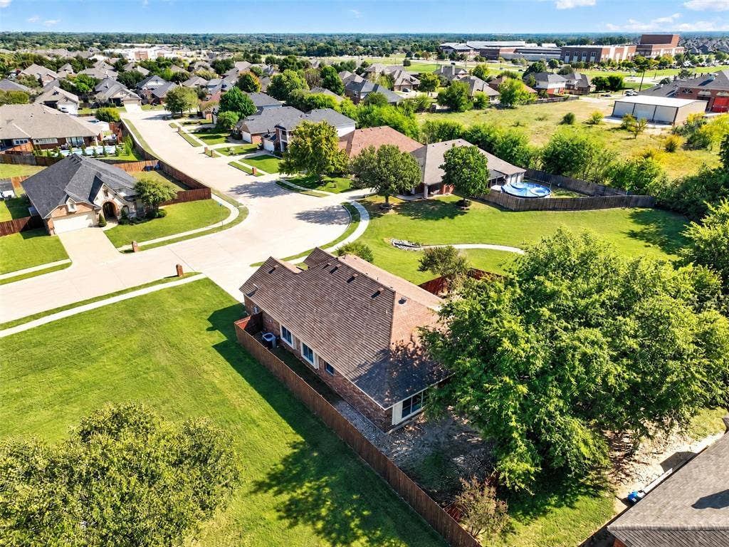 701 Abbey Lane, Midlothian, TX 76065 Aerial perspective of a brick exterior residence featuring a multi-gable roofline, wood-privacy fencing, and mature trees situated on a corner lot