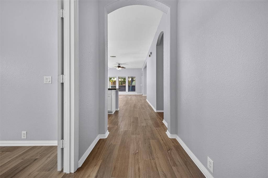 701 Abbey Lane, Midlothian, TX 76065 Interior hallway featuring arched architectural entryways, neutral-toned walls, and wood-finish flooring