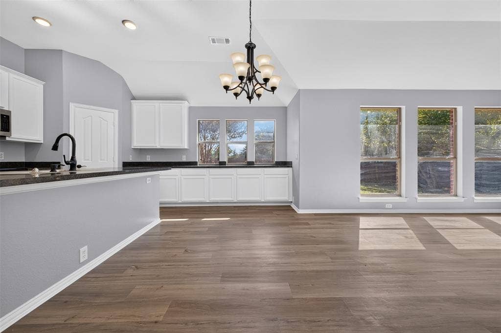701 Abbey Lane, Midlothian, TX 76065 Vaulted ceilings, wood-finish flooring, white cabinetry, dark countertops, and a multi-arm chandelier