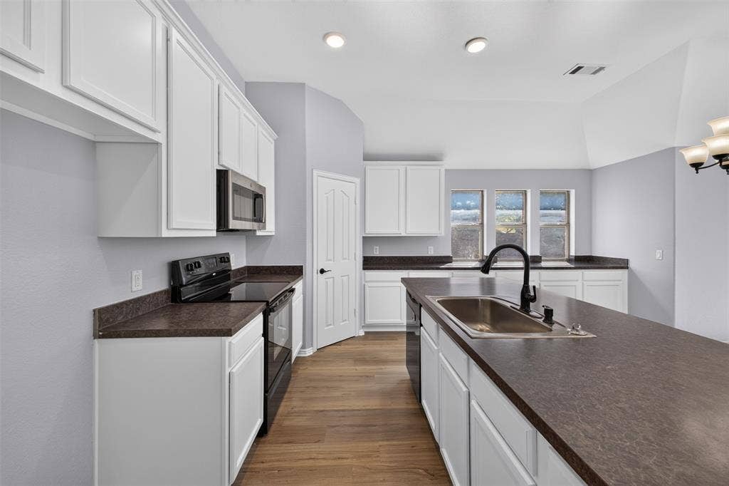 701 Abbey Lane, Midlothian, TX 76065 Kitchen featuring white cabinetry, dark solid-surface countertops, wood-finish flooring, a stainless steel undermount sink with a matte black faucet, and recessed lighting