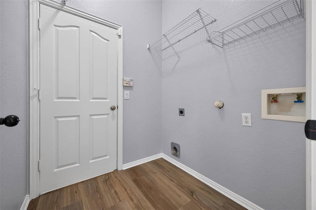 701 Abbey Lane, Midlothian, TX 76065 Utility room featuring wood-finish flooring, a four-panel door with a round knob, and wall-mounted wire shelving