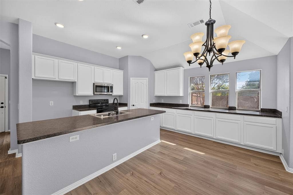 701 Abbey Lane, Midlothian, TX 76065 Kitchen featuring white shaker-style cabinetry, dark stone-finish countertops, wood-finish flooring, vaulted ceilings with a multi-arm chandelier, and recessed lighting