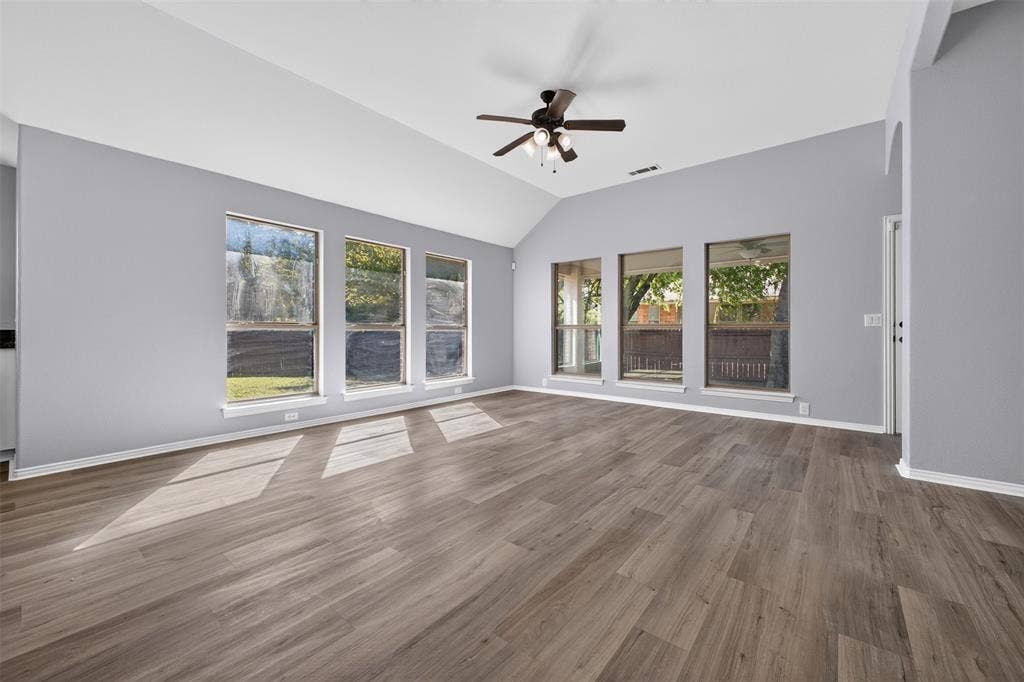 701 Abbey Lane, Midlothian, TX 76065 Vaulted ceiling, wood-finish flooring, six large windows, and a multi-blade ceiling fan with integrated lighting