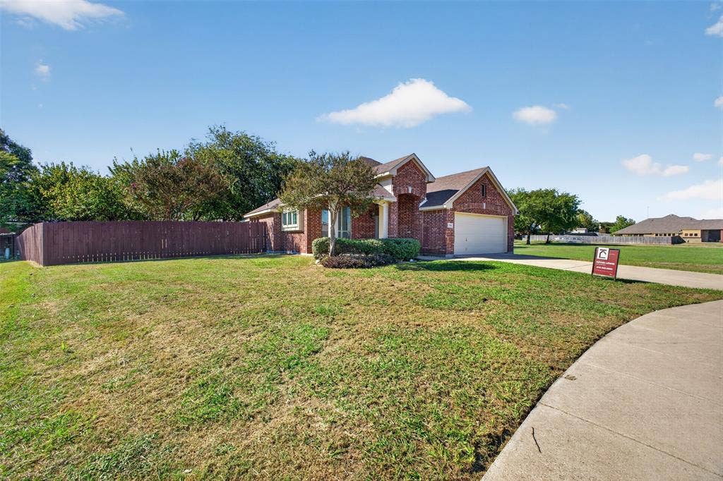 701 Abbey Lane, Midlothian, TX 76065 Single-story brick exterior featuring a multi-gable roofline, two-car garage, concrete driveway, and wooden perimeter fencing