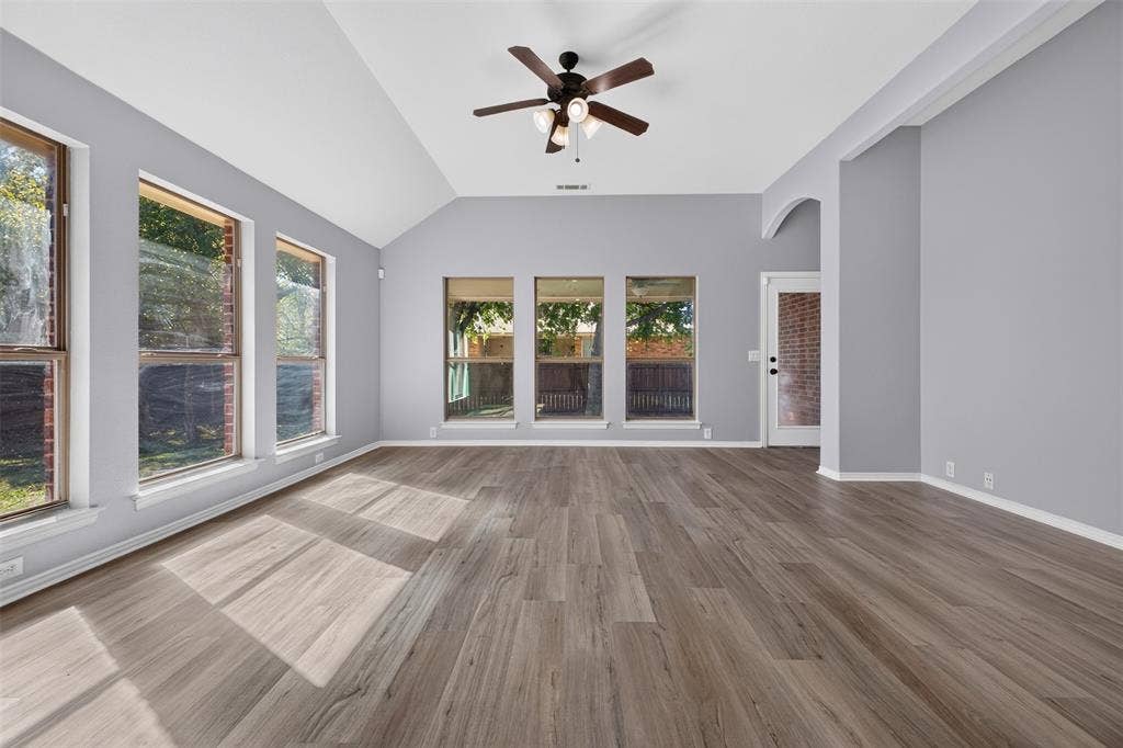 701 Abbey Lane, Midlothian, TX 76065 Vaulted ceiling featuring a central multi-blade ceiling fan, wood-finish flooring, and expansive windows