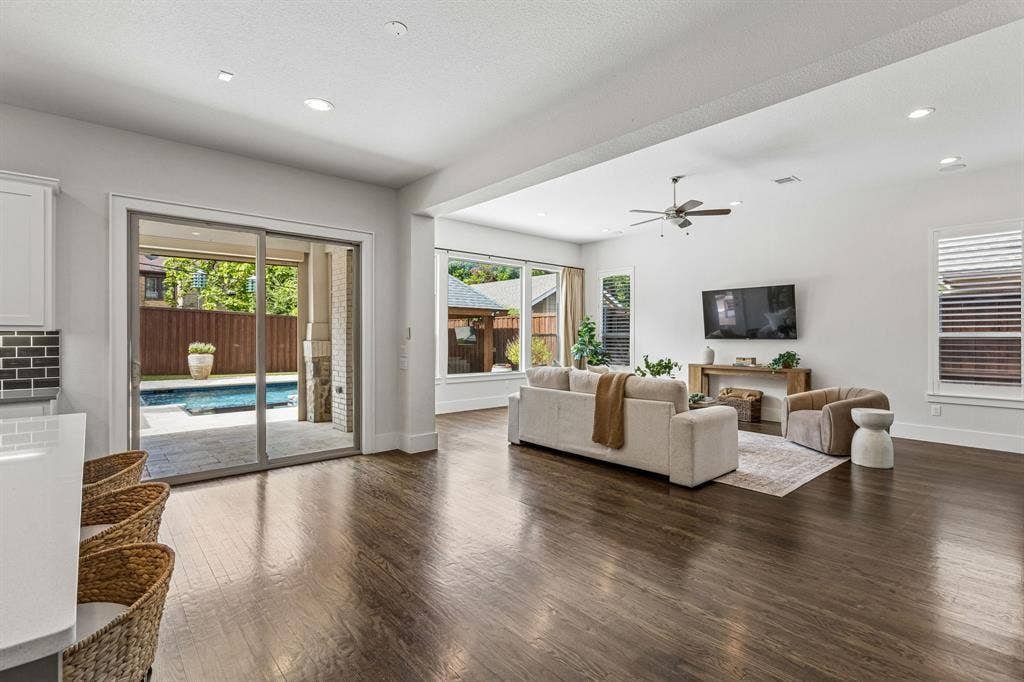 Open-concept interior featuring wood-finish flooring, recessed lighting, expansive glass sliding doors, and ceiling fan
