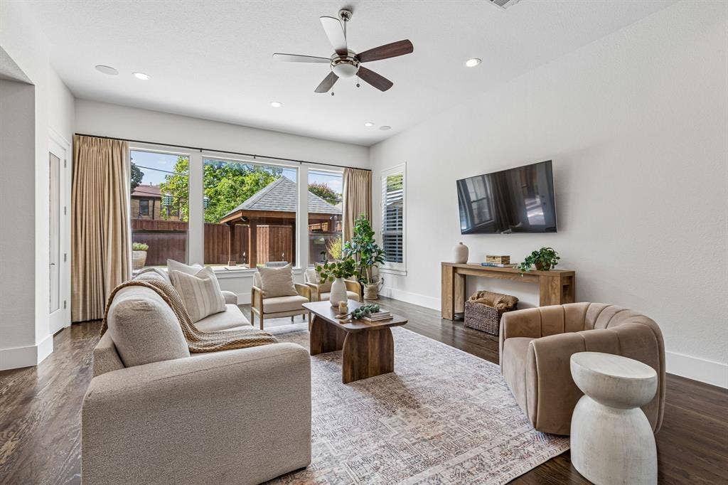 Open living space featuring wood-finish flooring, recessed lighting, a ceiling fan, and large windows