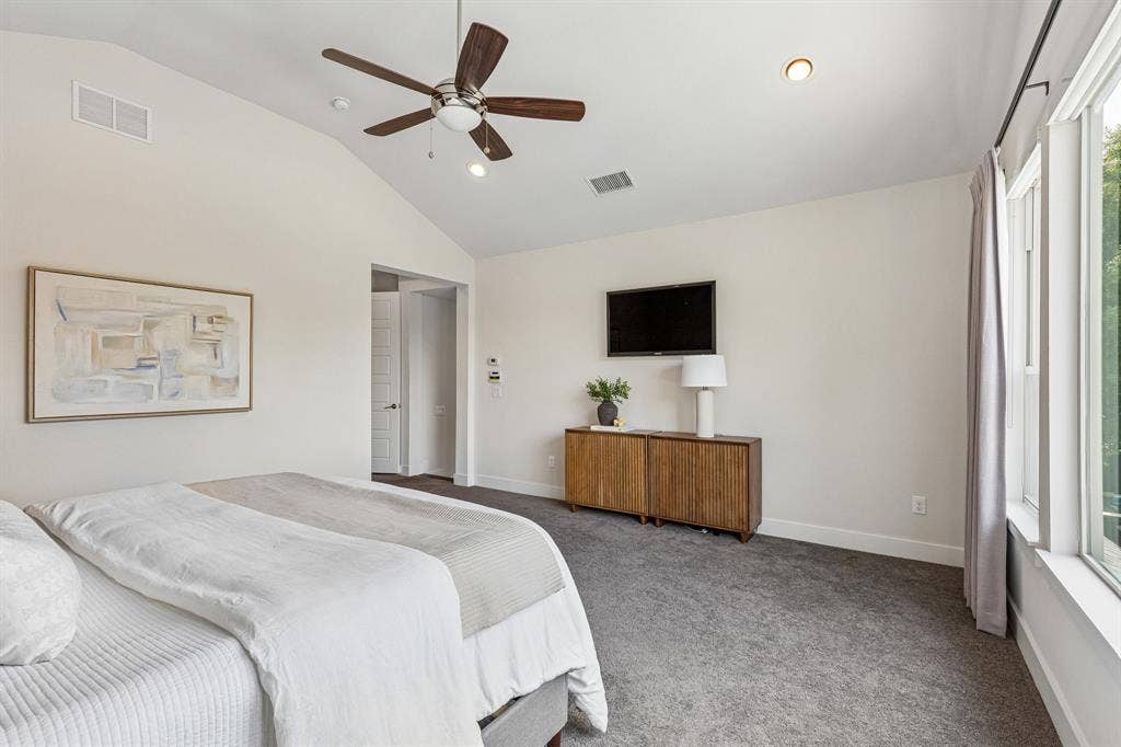 Vaulted ceilings, carpeted flooring, and a multi-blade ceiling fan with integrated lighting