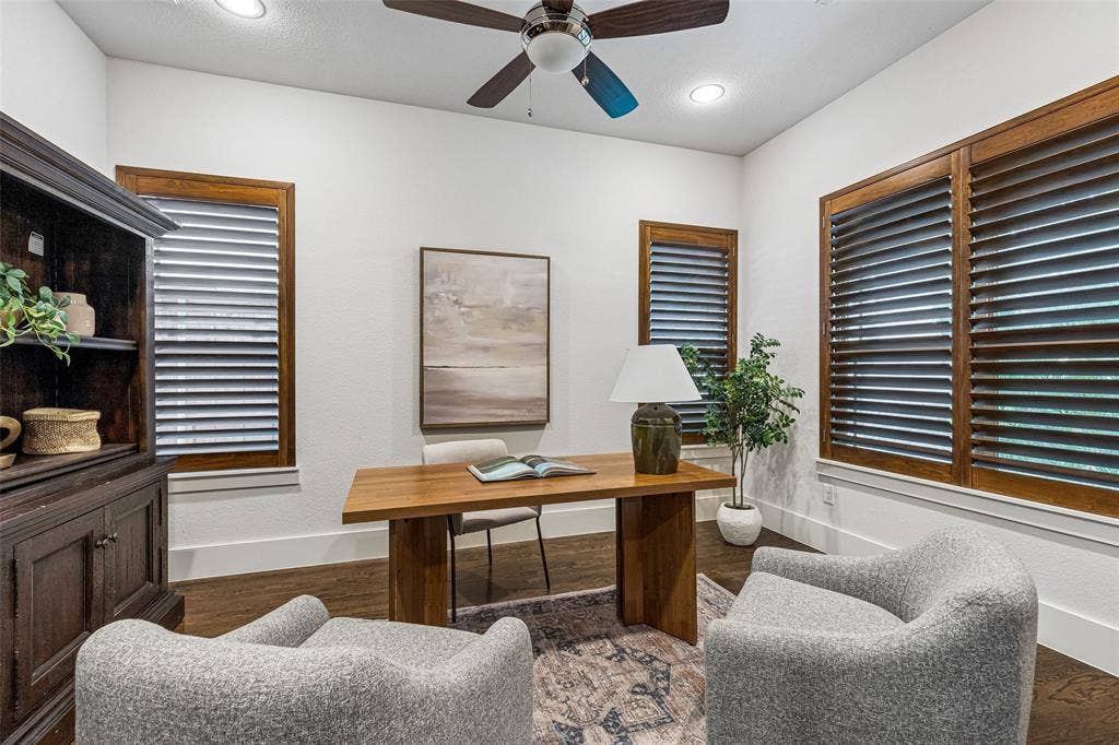 Room featuring wood-finish flooring, recessed lighting, a ceiling fan with integrated light fixture, and wood-framed windows outfitted with plantation shutters