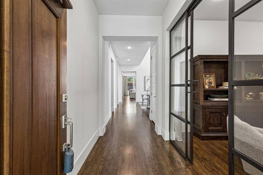Solid wood-finish front door with a metallic handle set, hardwood flooring, and metal-framed glass doors