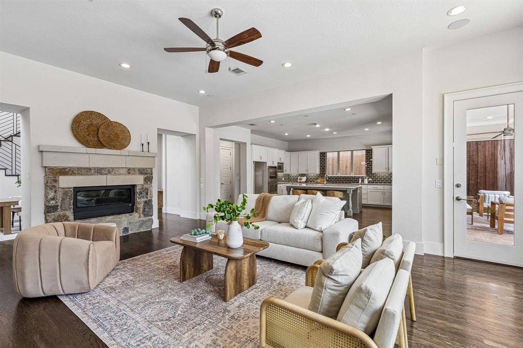 Living area featuring wood-finish flooring, stone-surround fireplace, recessed lighting, and a brushed nickel ceiling fan