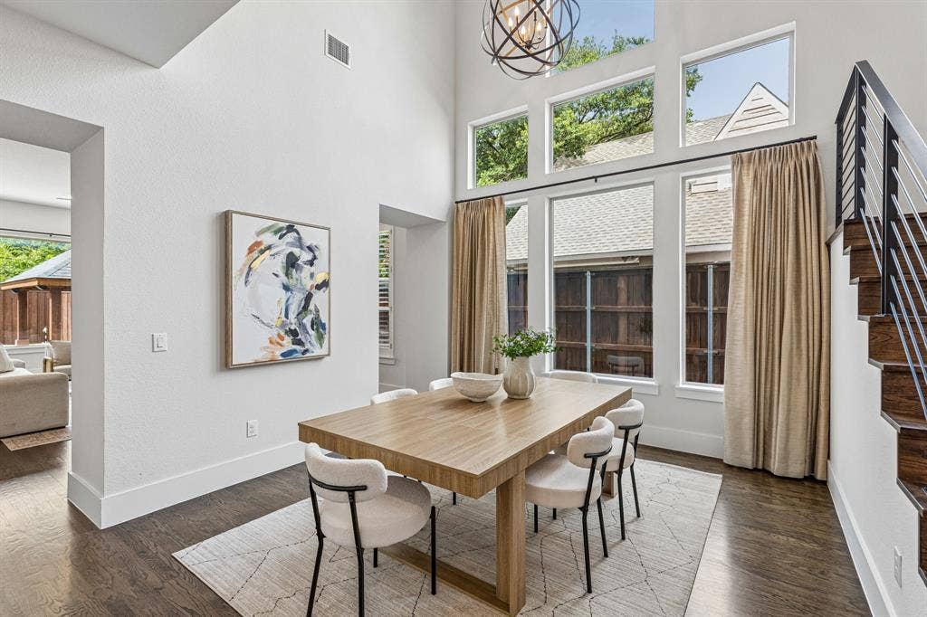 Double-height ceiling, tiered windows, wood-finish flooring, and architectural staircase with metal railing and wood treads