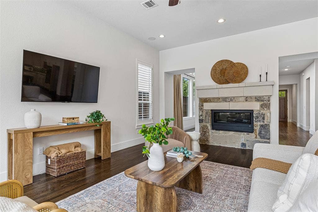 Living area featuring dark wood-finish flooring, recessed lighting, and a floor-to-ceiling stone fireplace surround with a custom masonry mantel