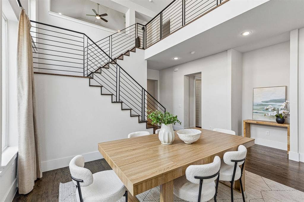 Double-height ceiling, open staircase with horizontal metal railing, wood-finish flooring, and recessed lighting
