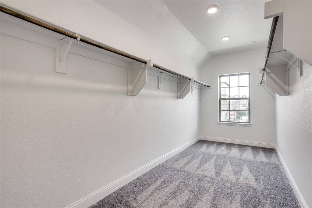 6341 Fortuna Lane, McKinney, TX 75070 Walk-in closet featuring patterned carpeting, dual-tiered built-in shelving with hanging rods, recessed lighting, and a multi-pane window