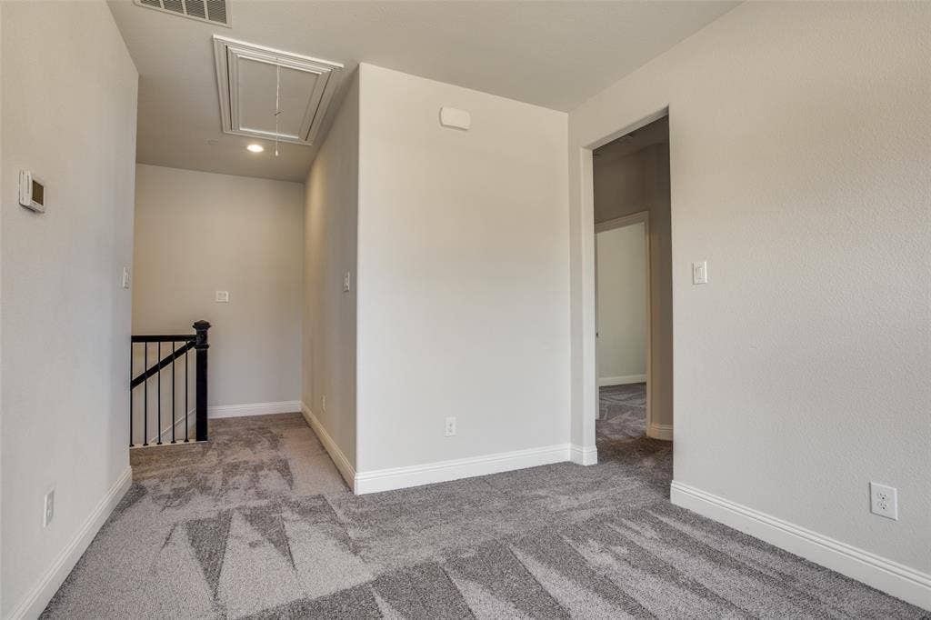 6341 Fortuna Lane, McKinney, TX 75070 Neutral-toned carpeting, matte black spindle stair railing, and ceiling attic access panel