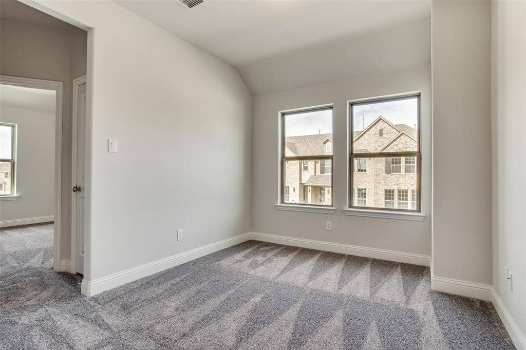6341 Fortuna Lane, McKinney, TX 75070 Neutral-toned interior space featuring neutral carpeting, a slanted ceiling, and dual-pane windows with trim