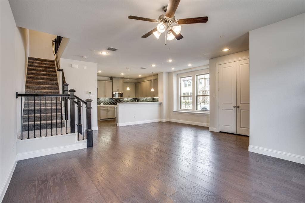 6341 Fortuna Lane, McKinney, TX 75070 Open-concept interior featuring wood-finish flooring, recessed lighting, a ceiling fan, a staircase with decorative metal balusters, and a kitchen with neutral cabinetry
