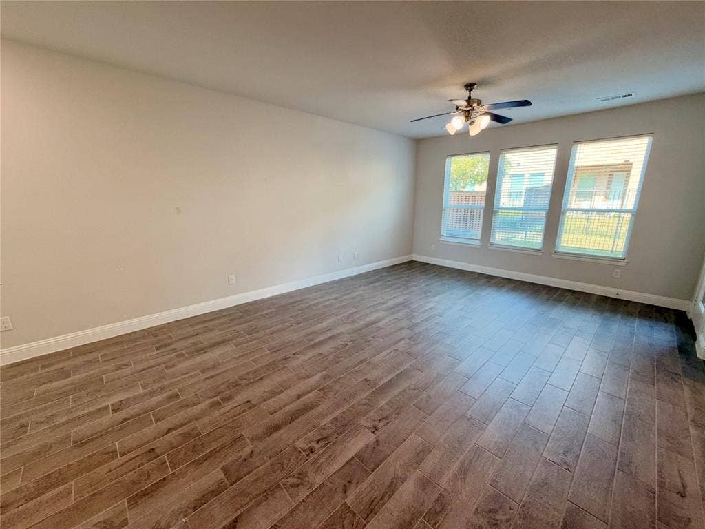 1063 Mj Brown Street, Allen, TX 75002 Interior space featuring wood-finish tile flooring, three large windows, and a multi-blade ceiling fan with integrated lighting