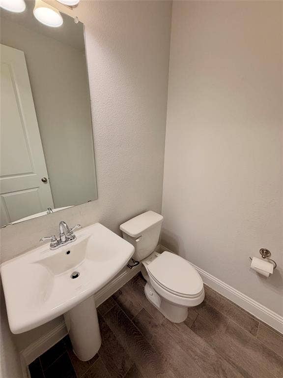 1063 Mj Brown Street, Allen, TX 75002 Pedestal sink with a polished chrome faucet, rectangular wall-mounted mirror, three-light vanity fixture, and wood-finish flooring