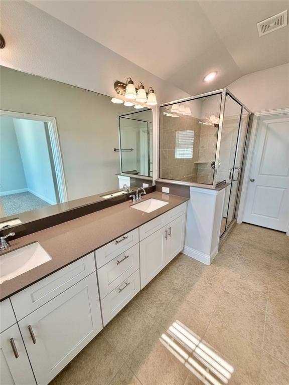 1063 Mj Brown Street, Allen, TX 75002 Dual-sink vanity with a solid-surface countertop, white shaker-style cabinetry, a glass-enclosed shower with tile surround, and tile flooring