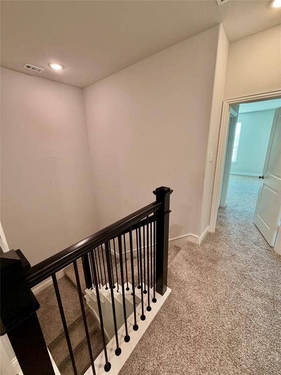 1063 Mj Brown Street, Allen, TX 75002 Staircase featuring dark-finished wooden handrails and balusters with carpeted steps, neutral wall tones, and recessed ceiling lighting