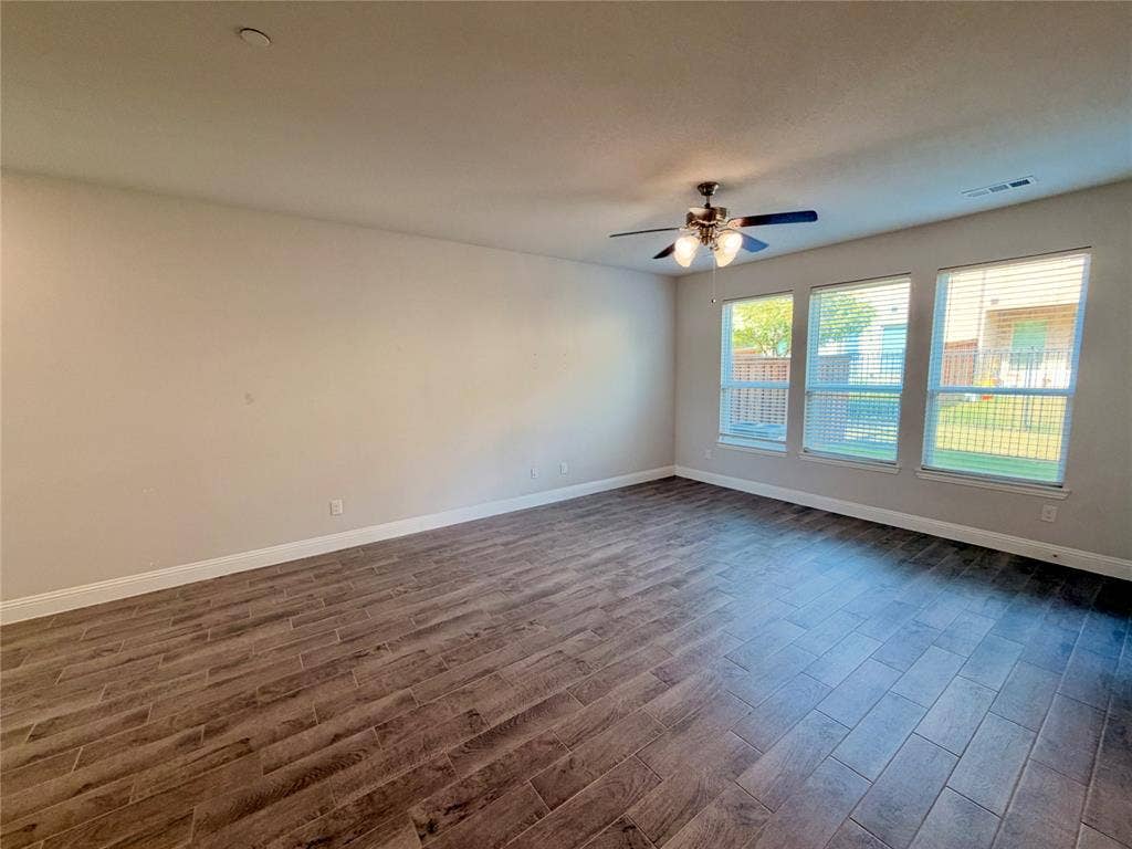 1063 Mj Brown Street, Allen, TX 75002 Spacious room featuring wood-finish flooring, neutral wall paint, three large windows, and a ceiling fan with integrated lighting