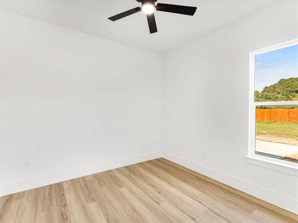 475 Loren Boyd Road, Combine, TX 75159 Bright interior space featuring wood-finish flooring, crisp white walls, a multi-blade ceiling fan, and a window with exterior landscape exposure