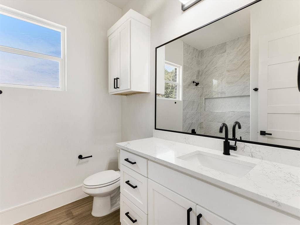 475 Loren Boyd Road, Combine, TX 75159 Bathroom vanity featuring a stone-surface countertop, integrated undermount sink, matte black hardware, and wood-finish flooring