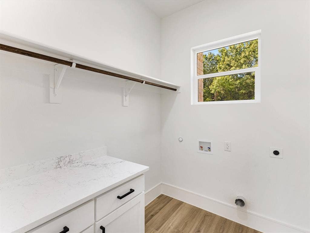 475 Loren Boyd Road, Combine, TX 75159 Utility room featuring white shaker-style cabinetry, a stone-patterned countertop, wood-finish flooring, a wall-mounted hanging rod, and a window