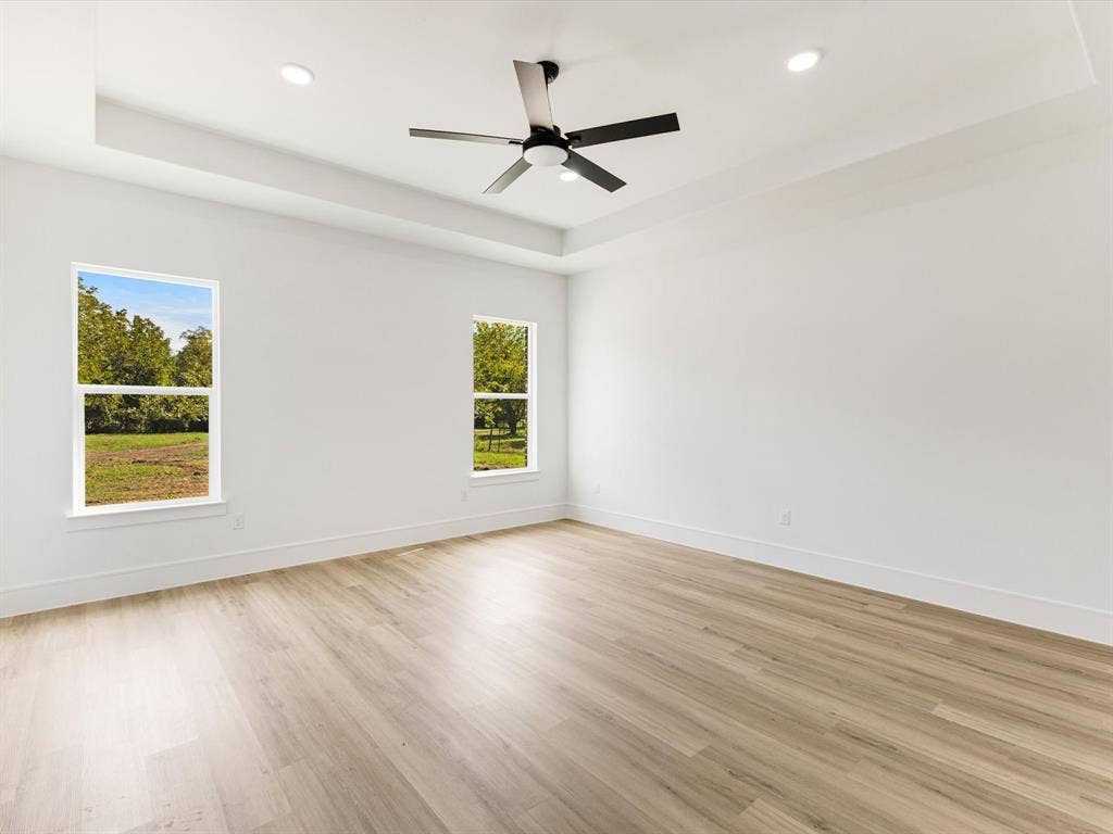 475 Loren Boyd Road, Combine, TX 75159 Tray ceiling featuring a central matte black ceiling fan, recessed lighting, wood-finish flooring, and windows with natural light