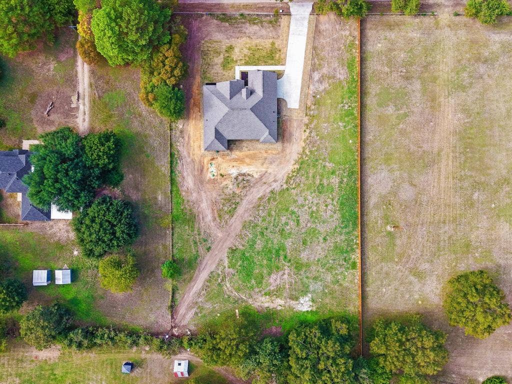 475 Loren Boyd Road, Combine, TX 75159 Aerial view of a residential property featuring a hipped roof structure, a paved concrete driveway, and expansive acreage enclosed by perimeter fencing