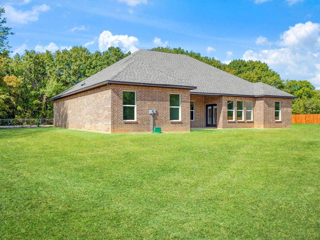475 Loren Boyd Road, Combine, TX 75159 Single-story brick exterior featuring a hipped roof, multi-pane windows, and a sprawling grass yard with perimeter tree growth