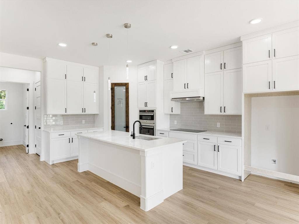 475 Loren Boyd Road, Combine, TX 75159 Kitchen featuring white Shaker-style cabinetry, a central island with a matte black faucet, subway tile backsplash, wood-finish flooring, and built-in stainless steel appliances