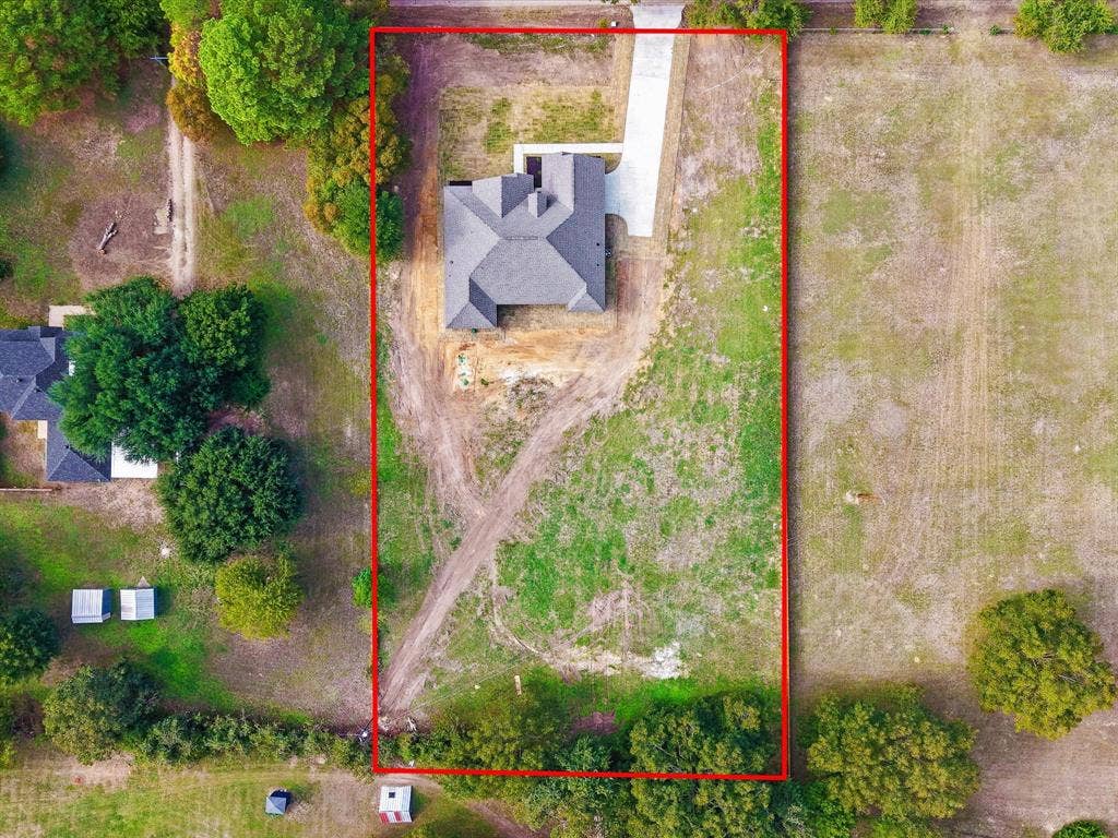 475 Loren Boyd Road, Combine, TX 75159 Aerial view of a rectangular property featuring a single-story structure with a multi-gable roof, concrete driveway, and expansive undeveloped land