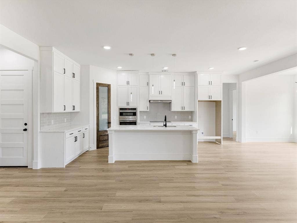 475 Loren Boyd Road, Combine, TX 75159 Kitchen featuring white ceiling-height cabinetry, a central island with a stone-finish countertop, wood-finish flooring, built-in stainless steel wall oven, and a pantry with a wood-toned door